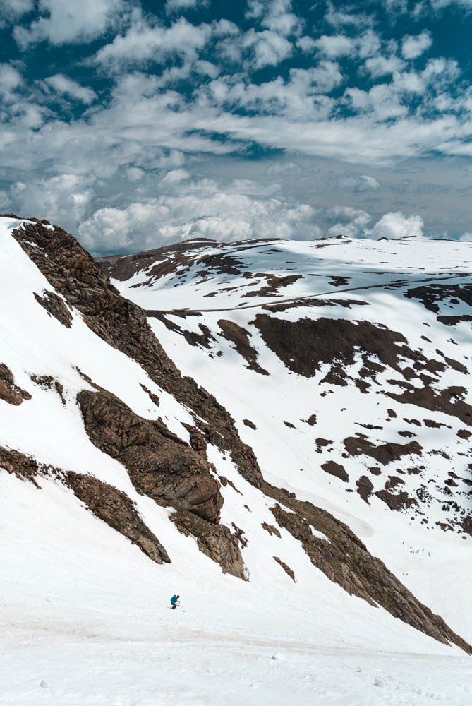 Steph skiing down Gardner Headwall with beautiful clouds